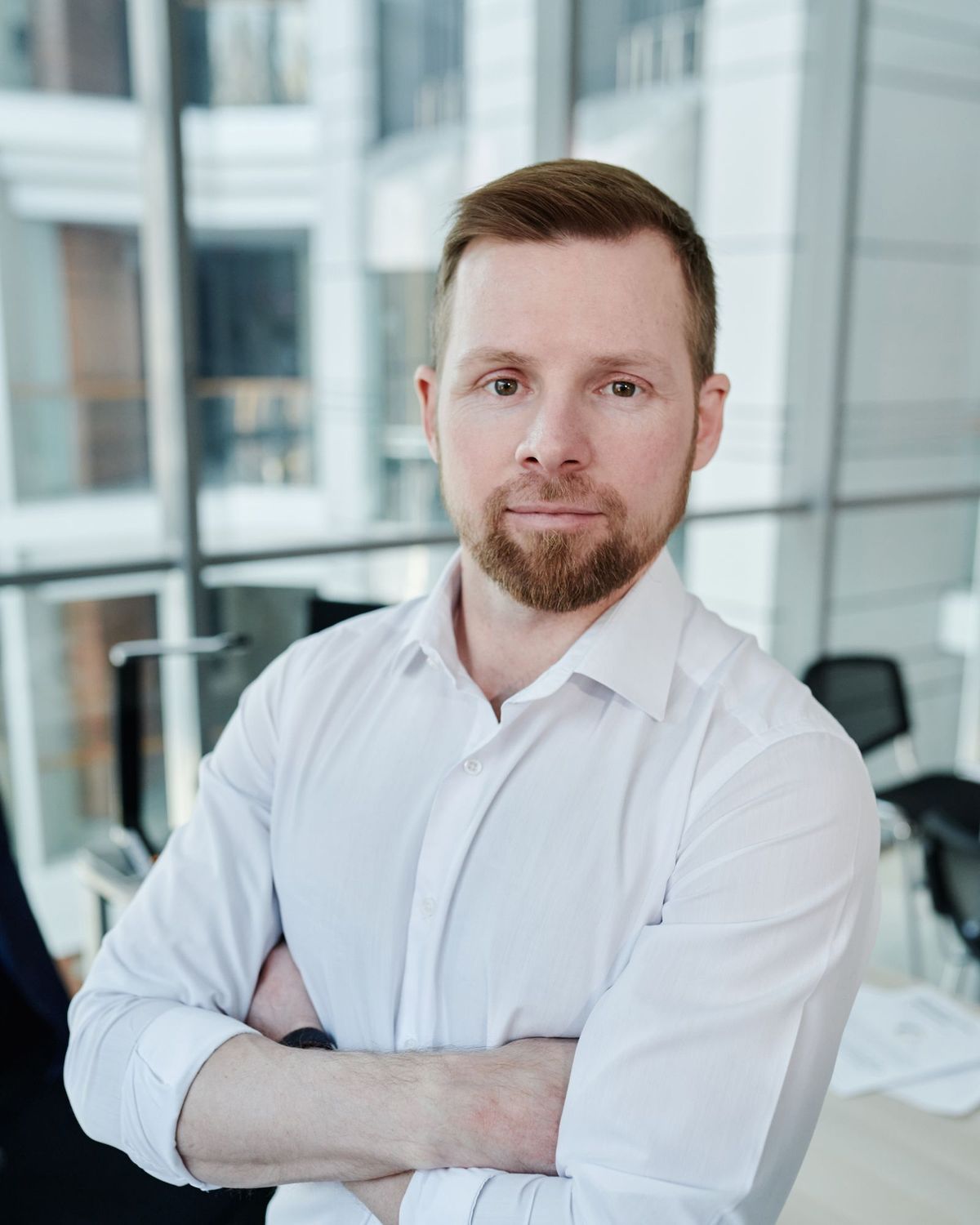 An accountant in a bright office, arms folded, friendly, cut out against light blue